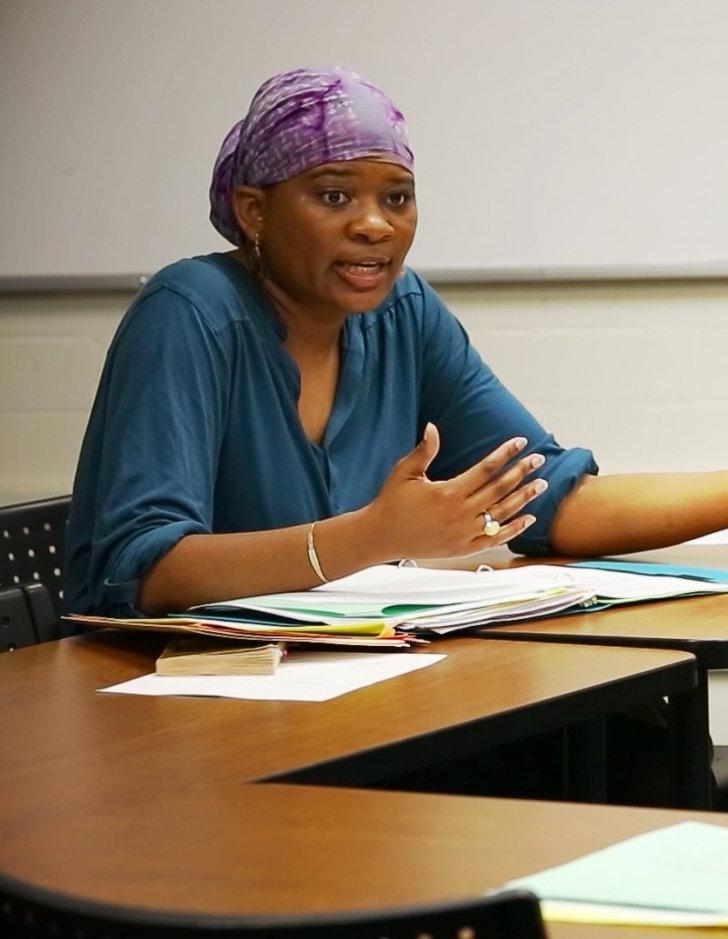 alicia bonaparte sits at a desk in a classroom