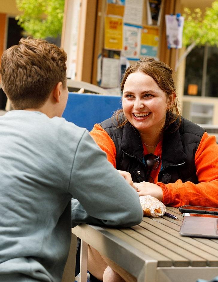 two students talk at a table in Scott courtyard